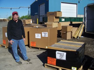 man standing in parking lot with large number of boxes around him