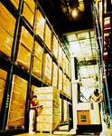 Warehouse full of boxes and man standing by forklift